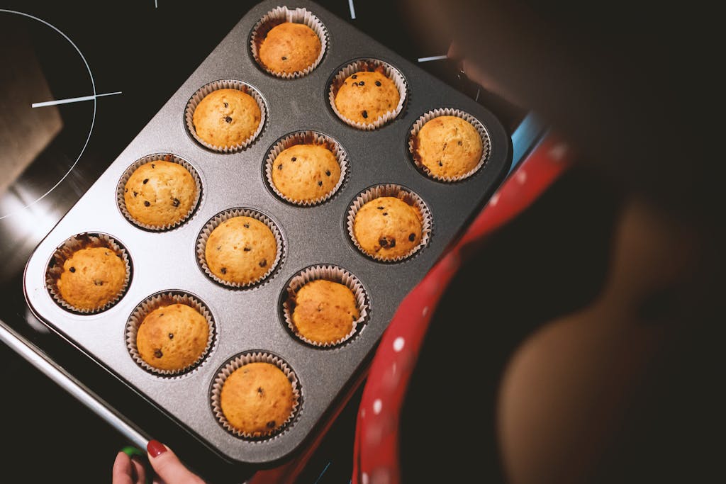 A tray of freshly baked chocolate chip muffins taken out of the oven.
