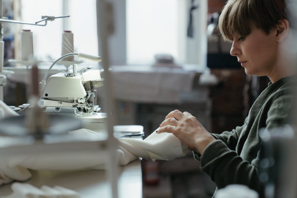 A tailor diligently working on a sewing machine in an indoor workshop setting.