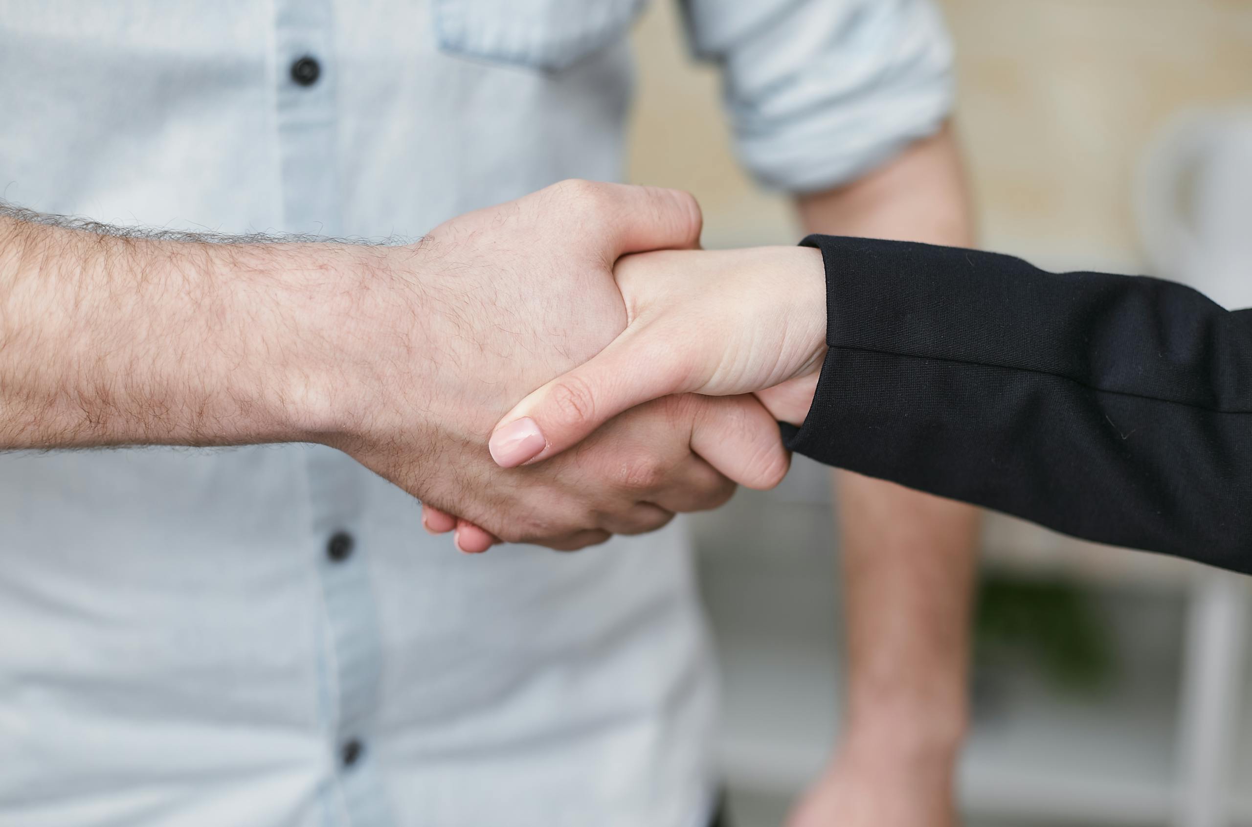 Close-up of two individuals shaking hands symbolizing business agreement and partnership.