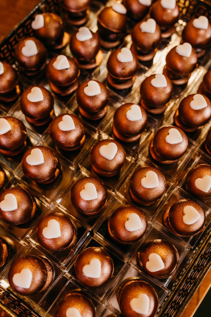 Delicious chocolate bonbons with heart decorations arranged in a grid pattern.