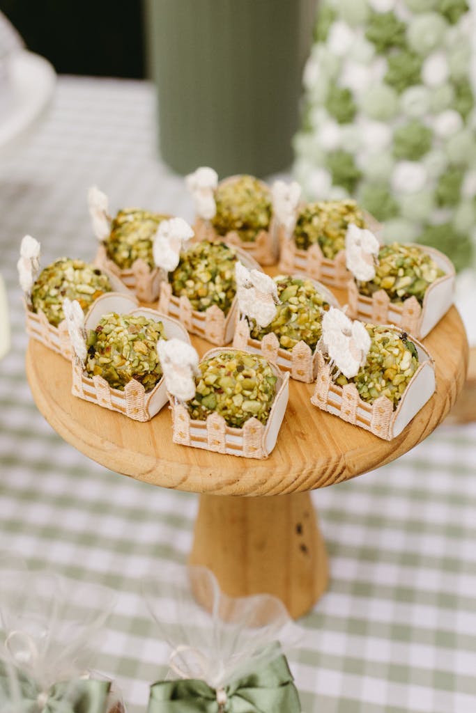 Delicious pistachio bonbons elegantly displayed on a wooden stand for a chic celebration.
